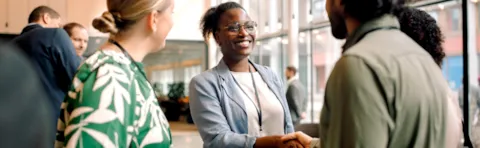 Businesswoman shaking hands with male entrepreneur during networking event