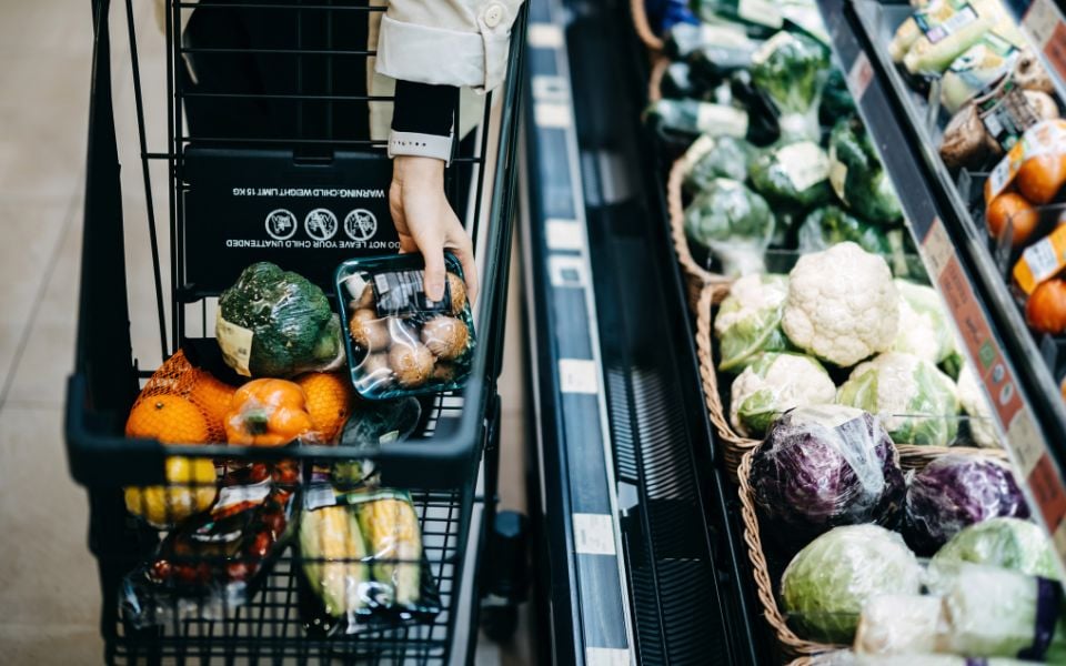 Carrello della spesa nel reparto verdure del supermercato